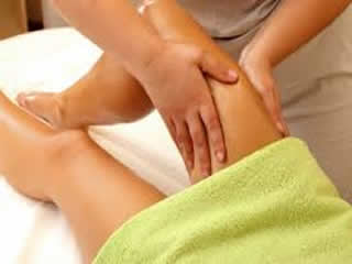 Therapist performing traditional Thai leg massage on client lying down