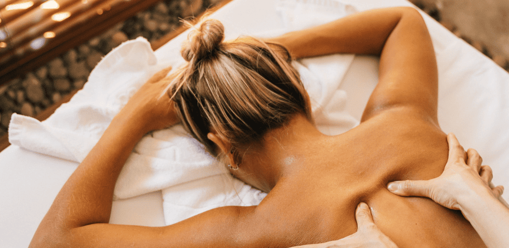 Therapist performing traditional Thai massage on client lying on floor mat