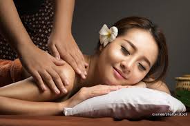 Thai massage therapist performing traditional stretching technique on clients leg.